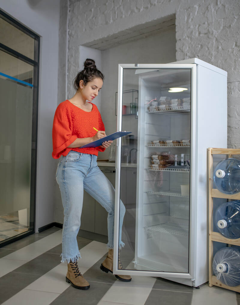 worker checking the reach in cooler inventory