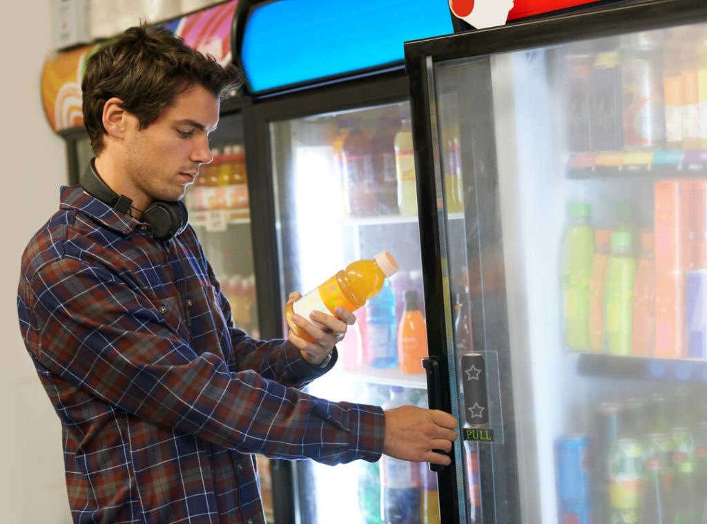 customer selecting a drink from a reach in cooler at the convenience store